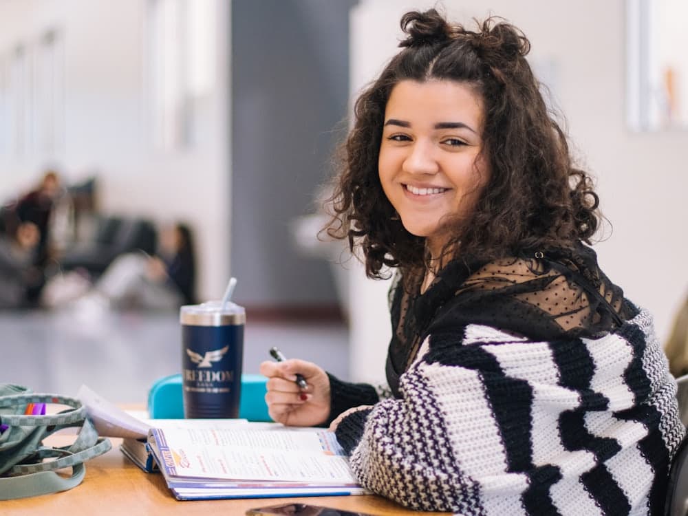 Estudiante sonriendo con sus cuadernos