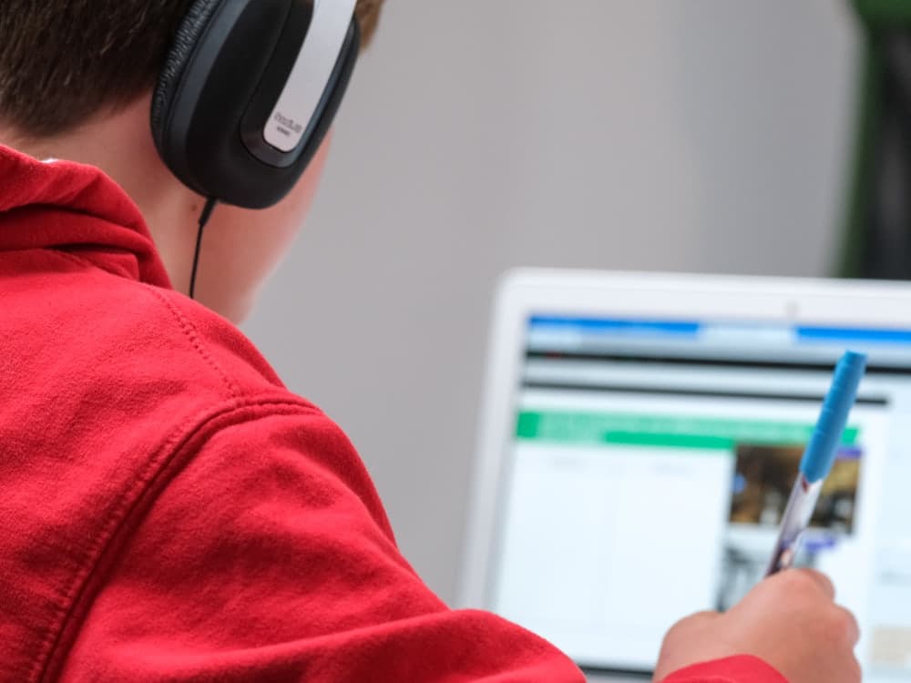 Niño con audífonos estudiando en computador